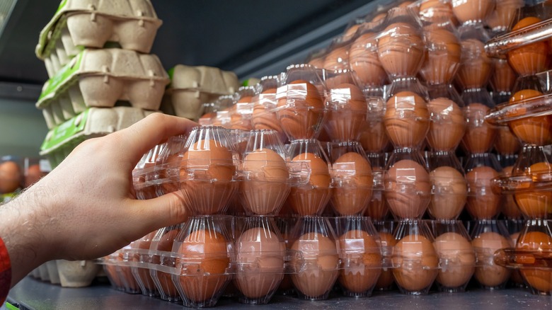 Person grabbing clear plastic egg cartons