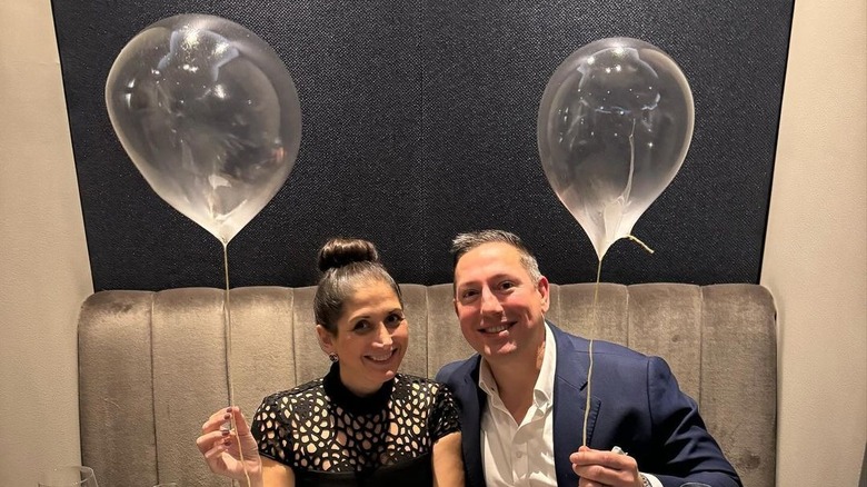 Couple eating dinner at Alinea and holding edible helium balloons