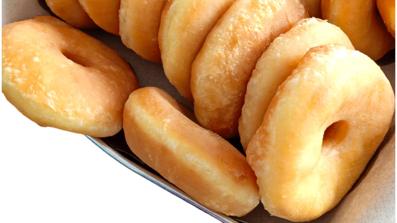 Glazed doughnuts are lined up in a container.