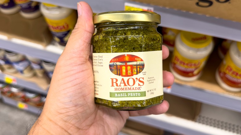 A grocery shopper holding a jar of Rao's pesto