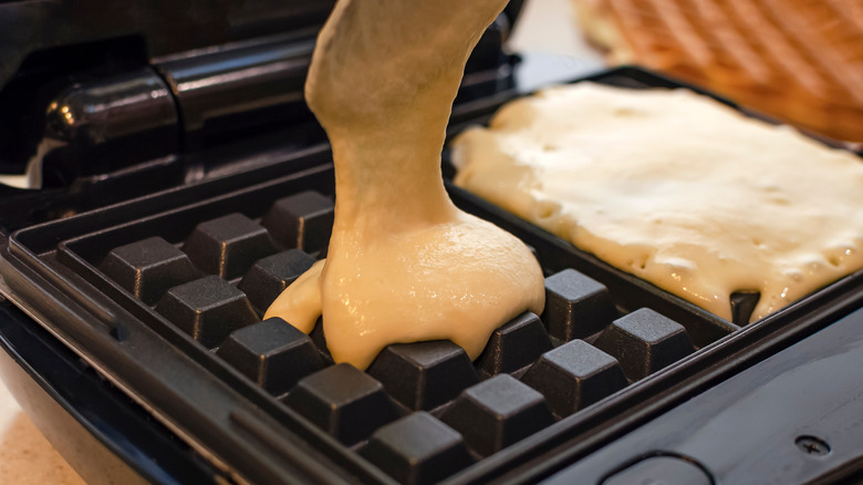 Pouring fluffy waffle batter into waffle iron