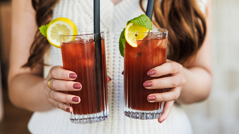 Two glasses of black iced tea with lemon and mint