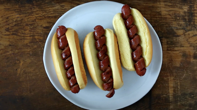 Two hot dogs have been spiralized and sit against a white background