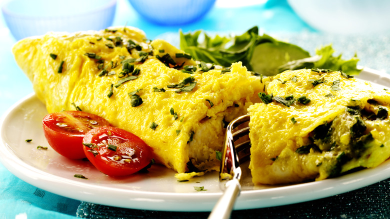 Omelet on a plate with a fork cutting it.