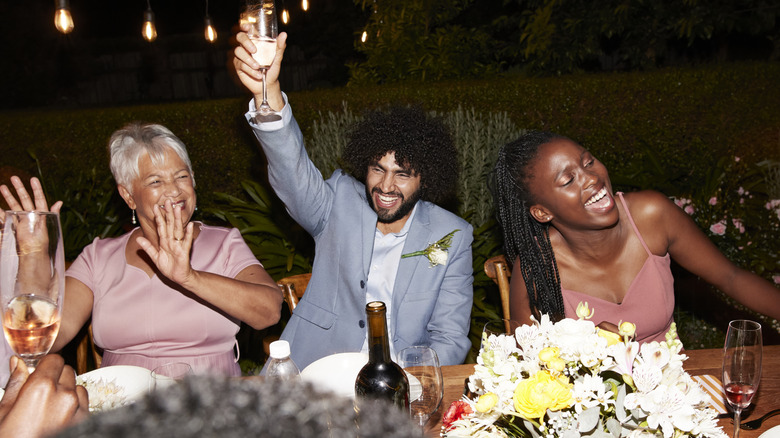 Exuberant guests at an evening dinner table outdoors