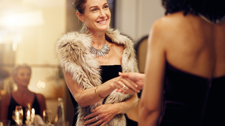 Two women shake hands at formal dinner