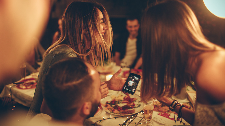 Party guests laughing at image on cell phone