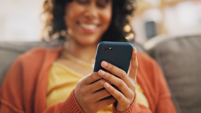 Woman in orange sweater typing on her phone