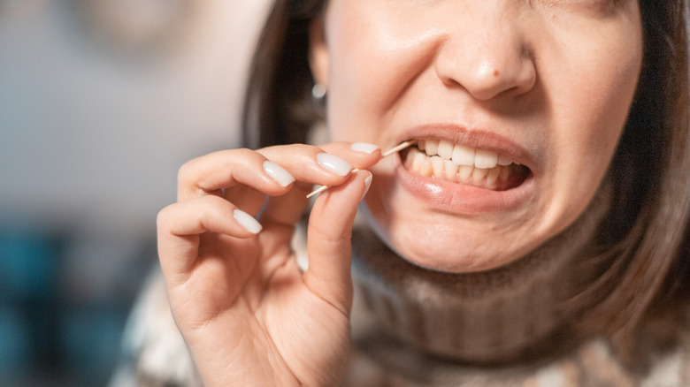 Woman using toothpick to get food out of teeth