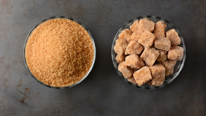 A bowl of turbinado sugar next to brown sugar cubes