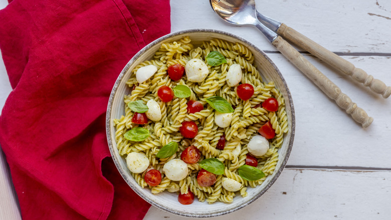 A bowl of pasta salad includes tomatoes and mozzarella.