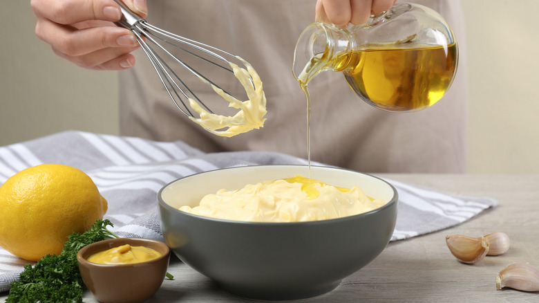 Pouring oil into bowl of mayonnaise