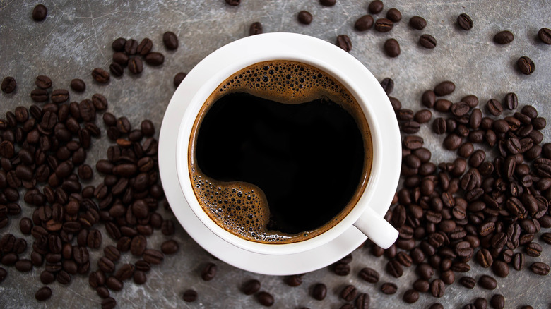 Cup of coffee with coffee beans on table