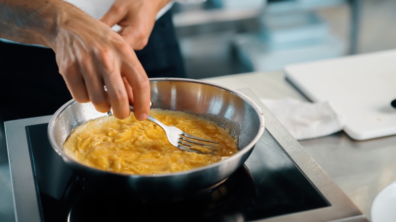 Making a French style omelette in a pan with a fork