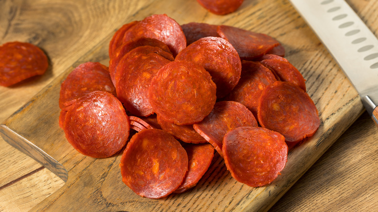 sliced pepperoni sitting on wooden cutting board