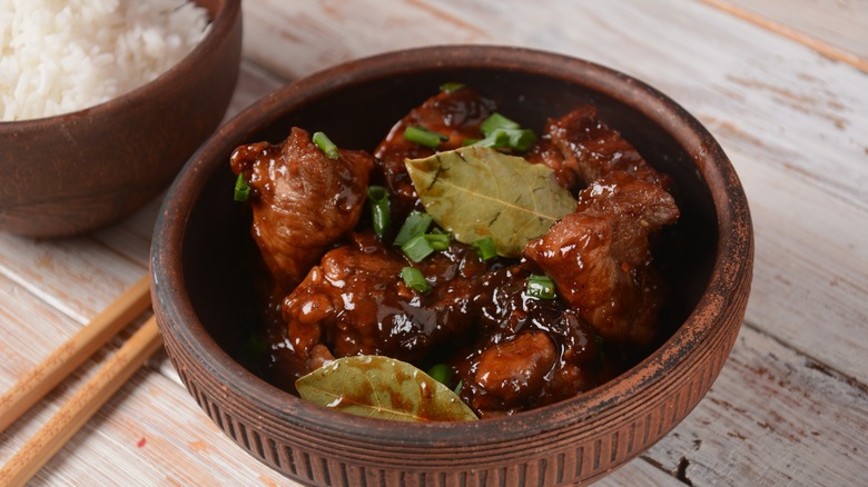 Filipino adobo in a clay bowl with rice