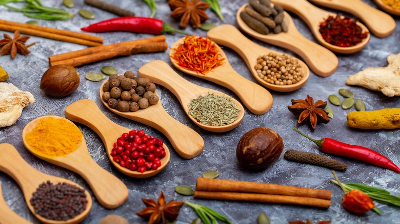 whole spices in wooden spoons on gray tablecloth