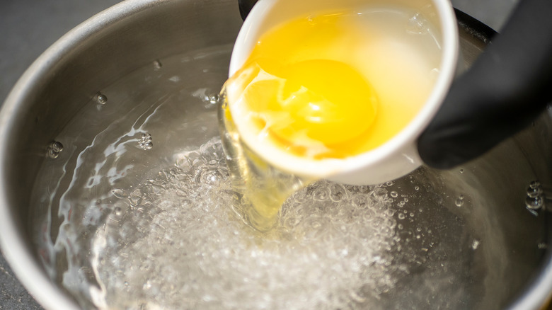 Dropping egg into poaching water