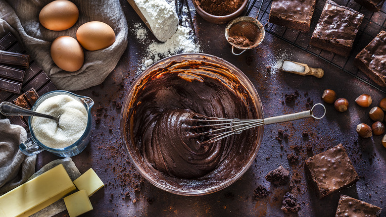 whisk inside brownie batter on busy counter