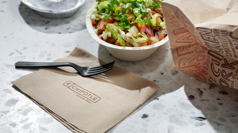 Chipotle bowl with logo napkin and fork.