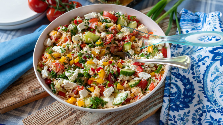 A Mediterranean rice bowl with cucumbers, feta, tomatoes, and bell peppers