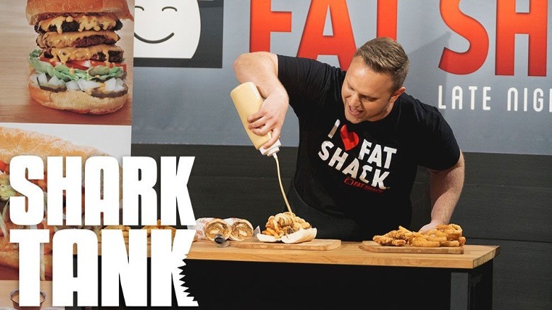 Owner of Fat Shack pouring sauce on sandwich