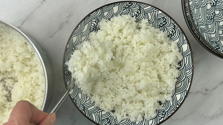 hand spooning rice into bowl