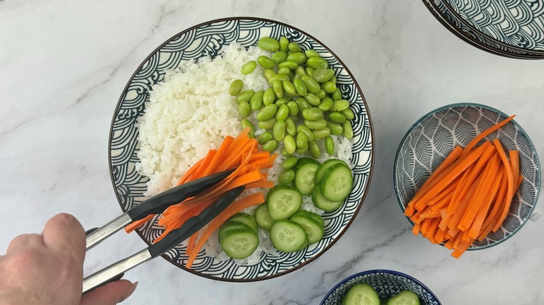 hand putting carrots on rice