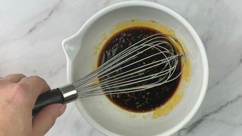 hand stirring sauce in bowl