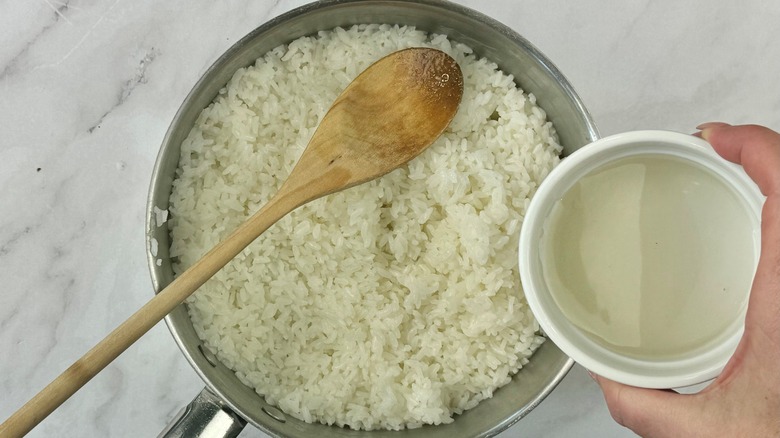 hand holding liquid above rice