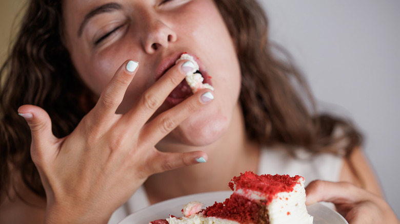 Woman licking cake icing off her fingers