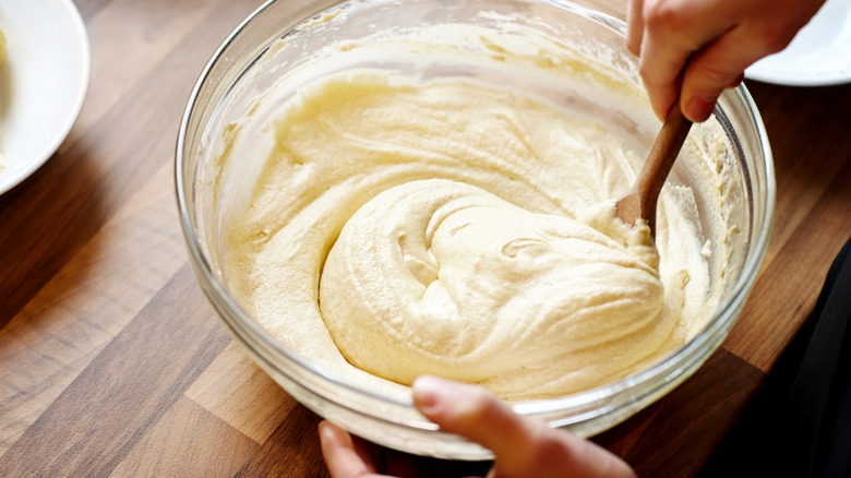 Mixing vanilla cake batter in a glass bowl with wooden spoon