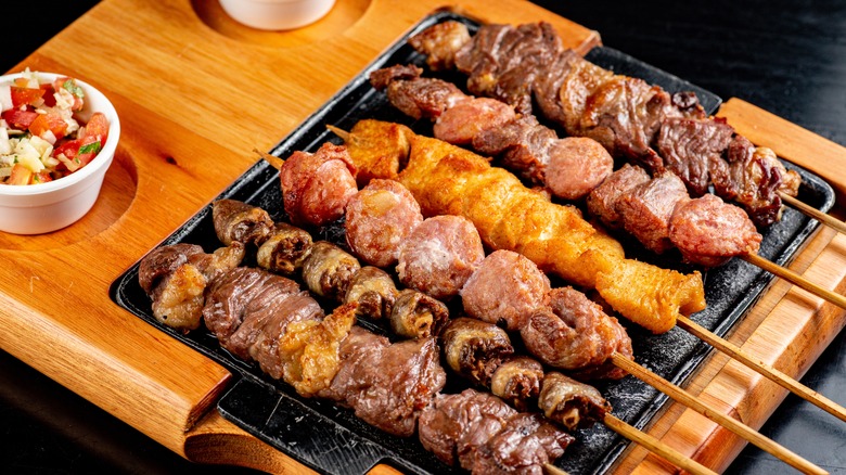 An array of different meat kebabs on metal platter