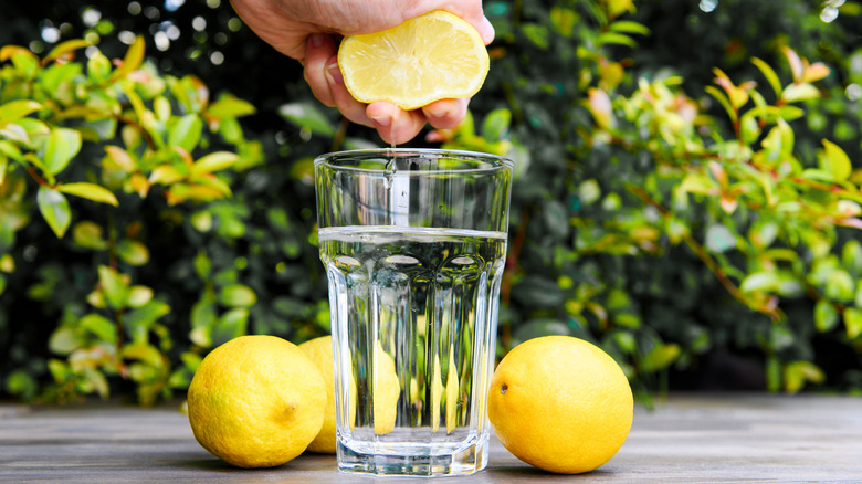 Squeezing a lemon into glass of water