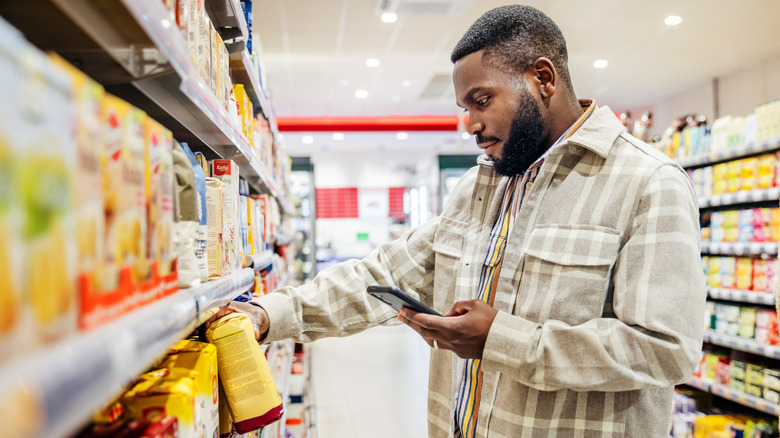 Man grocery shopping and checking phone