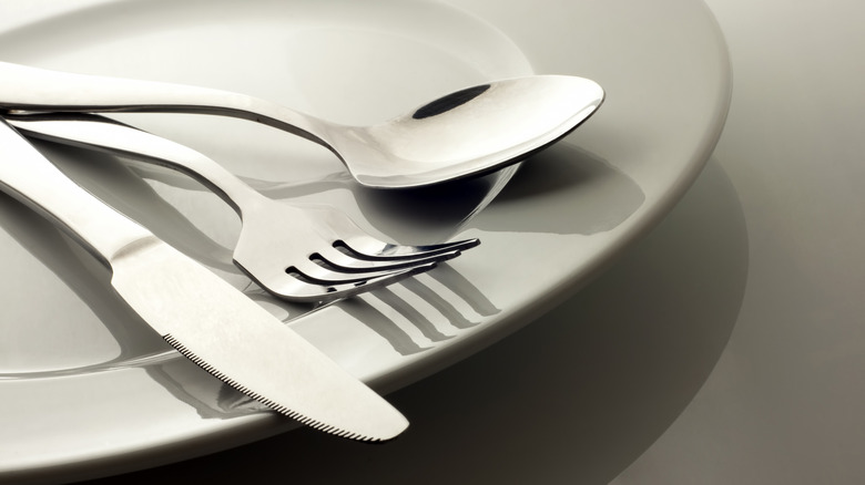 spoon, fork, and knife resting on plate