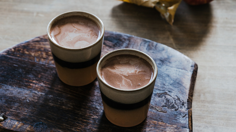 Hot chocolate in white and blue striped ceramic cups on wooden board