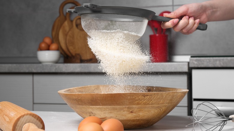 Sifting flour into wooden bowl