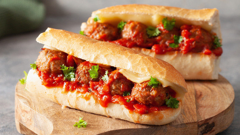 Two meatball subs on wooden board