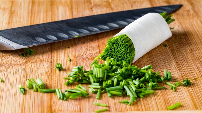 Sliced chives wrapped in paper towel on cutting board