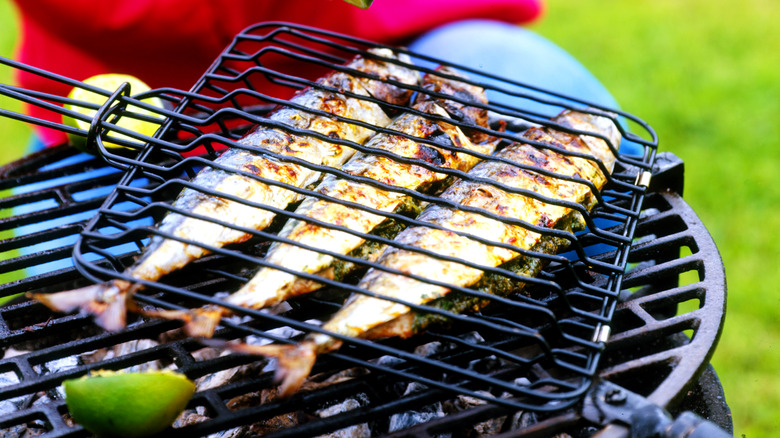 Three whole fish in a basket on the grill