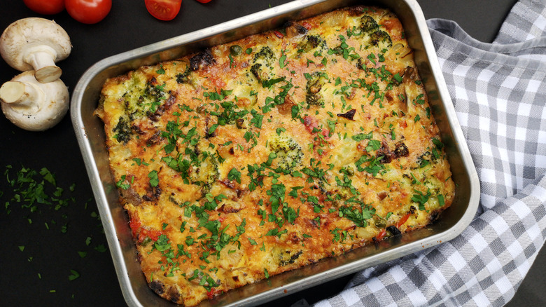 Frittata with vegetables baked on oven tray on dark table