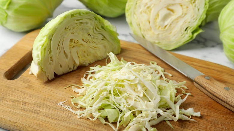 a halved cabbage head next to shredded cabbage 