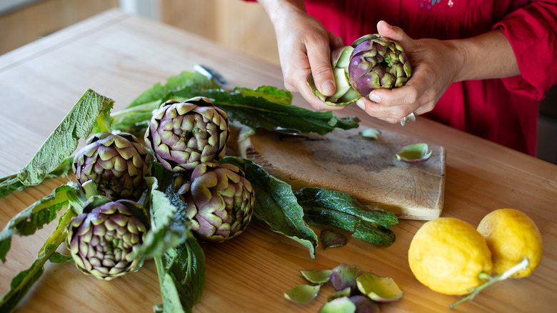 A woman is turning artichokes.