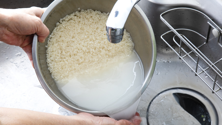 Washing rice in sink with tap water