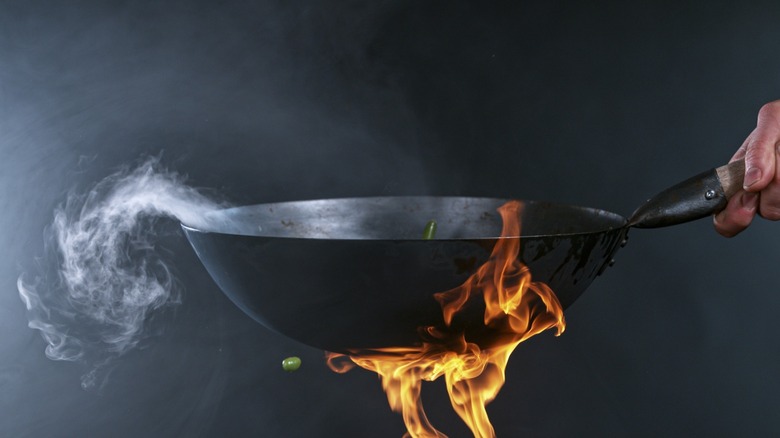 Black wok held over flame