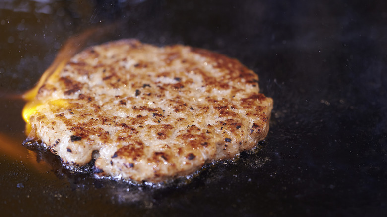 Burger patty sizzles on griddle