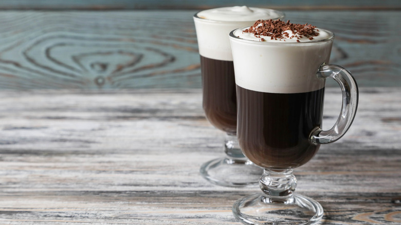 two glasses of traditional Irish coffee, and one is topped with chocolate shavings