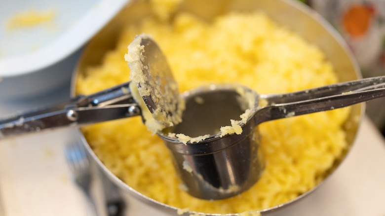 a ricer mashing potatoes into a pot