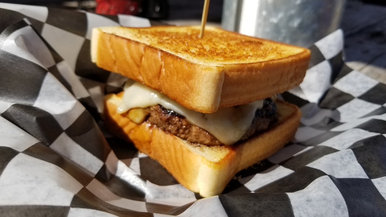 a cheese burger on checkered paper in garlic bread